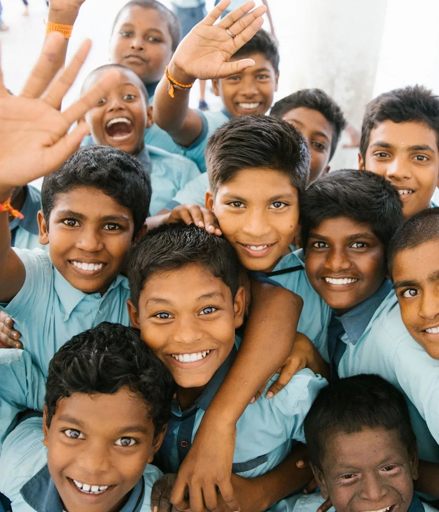 Schoolboys in uniform laughing and waving back home in Kochi